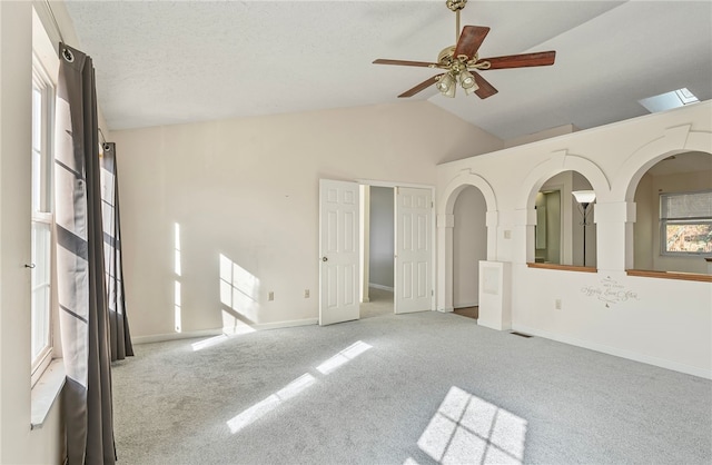 carpeted empty room with ceiling fan and vaulted ceiling