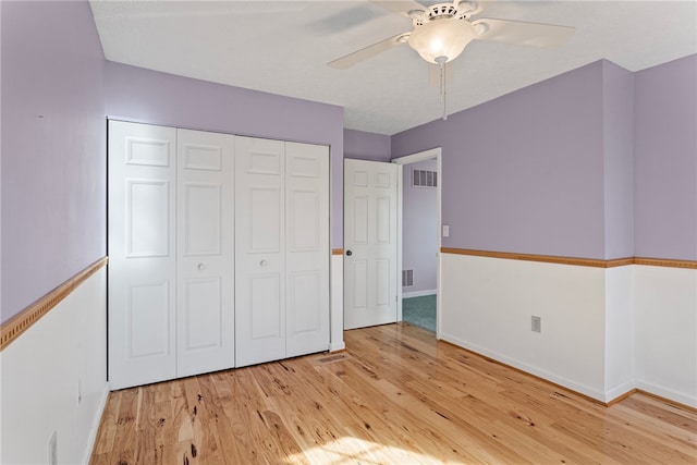 unfurnished bedroom featuring ceiling fan, a closet, and light wood-type flooring