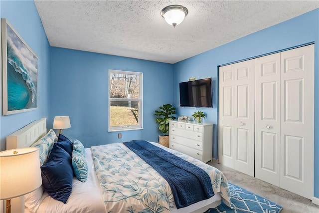 carpeted bedroom with a textured ceiling and a closet