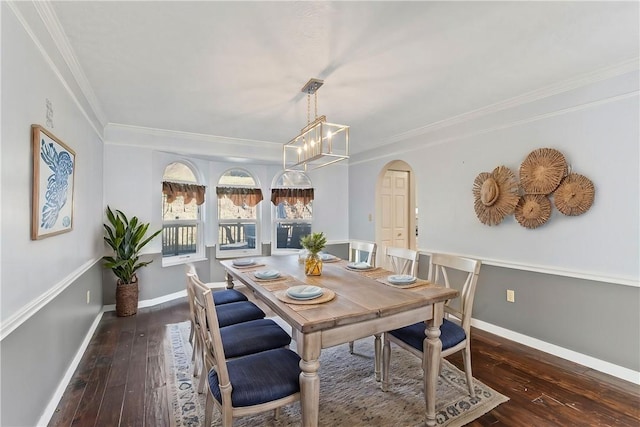 dining space featuring dark wood-type flooring, an inviting chandelier, and ornamental molding