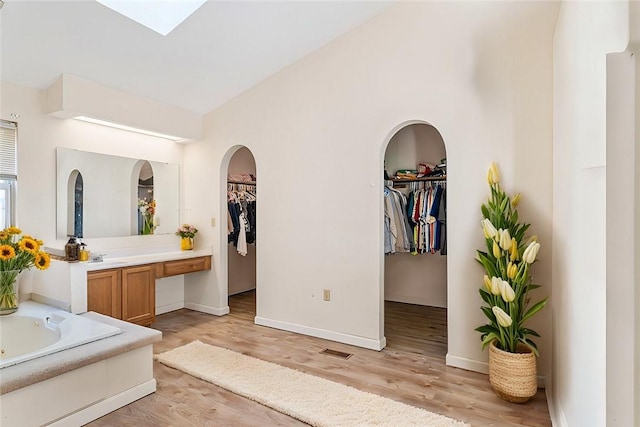 bathroom featuring a skylight, hardwood / wood-style floors, vanity, and a bathing tub