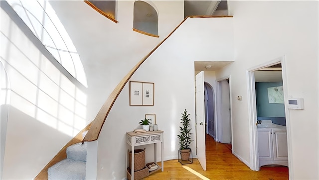 stairs with wood-type flooring and a towering ceiling