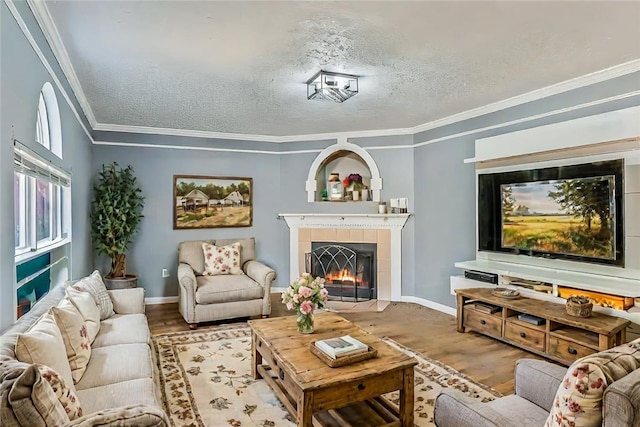 living room with a textured ceiling, a tile fireplace, crown molding, and light hardwood / wood-style flooring