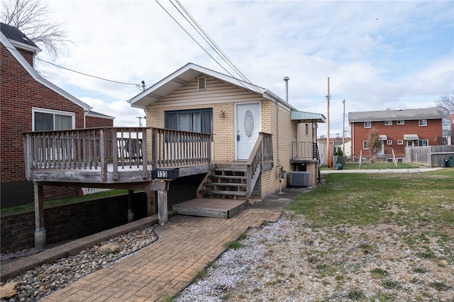 view of front of property featuring a front yard, central AC unit, and a wooden deck