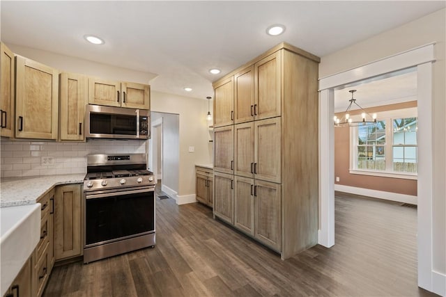 kitchen with decorative backsplash, light stone counters, stainless steel appliances, a chandelier, and dark hardwood / wood-style floors