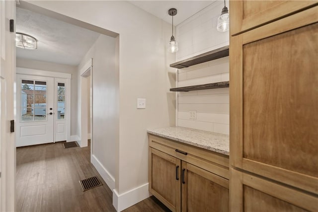 bar with light stone countertops, decorative light fixtures, dark hardwood / wood-style flooring, and tasteful backsplash