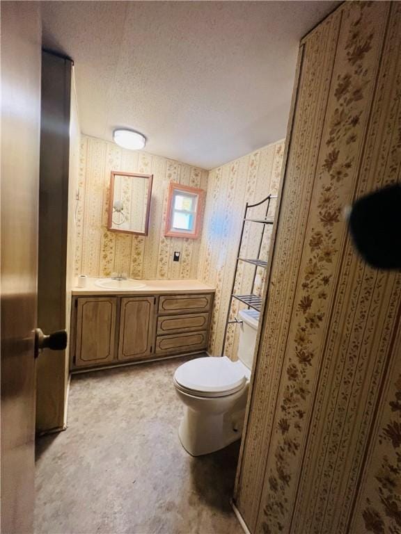 half bath with vanity, toilet, and a textured ceiling