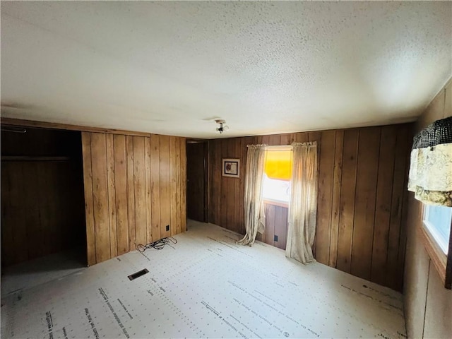 spare room with wooden walls and a textured ceiling