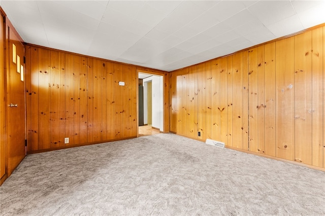 carpeted empty room with wood walls