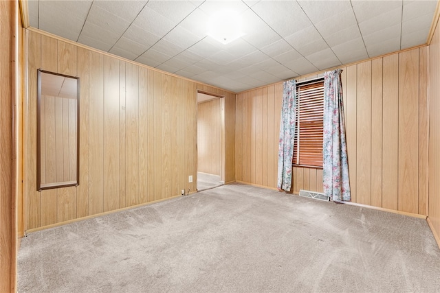 carpeted spare room with wooden walls