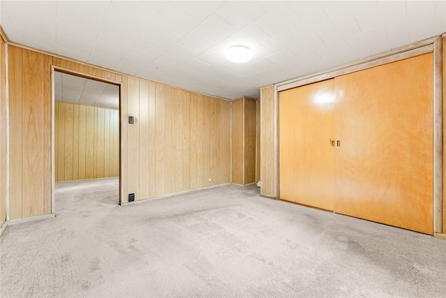 carpeted spare room with wood walls