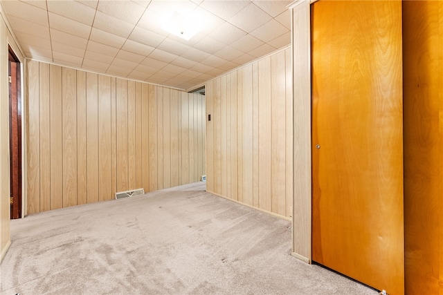 unfurnished room featuring light carpet and wood walls