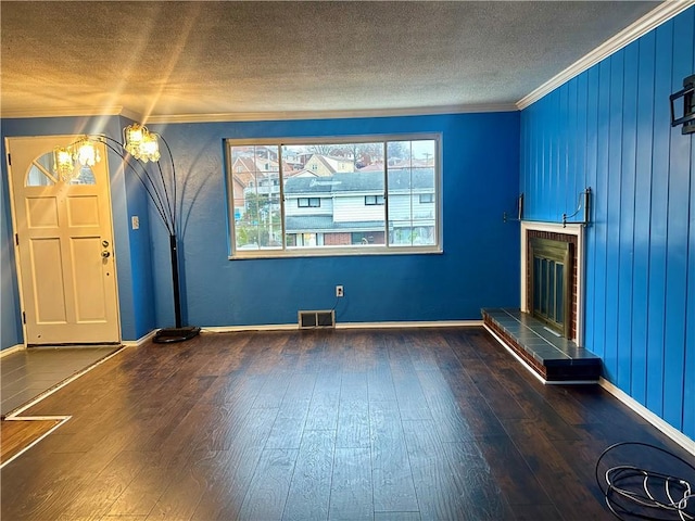 unfurnished living room with a fireplace, wood-type flooring, a textured ceiling, and ornamental molding