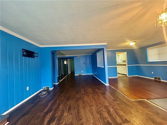 empty room featuring hardwood / wood-style floors, crown molding, and a textured ceiling