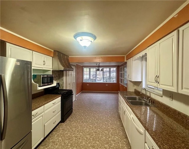 kitchen with dark stone counters, white cabinets, wall chimney range hood, sink, and appliances with stainless steel finishes