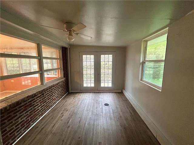 interior space featuring french doors, ceiling fan, dark wood-type flooring, and brick wall