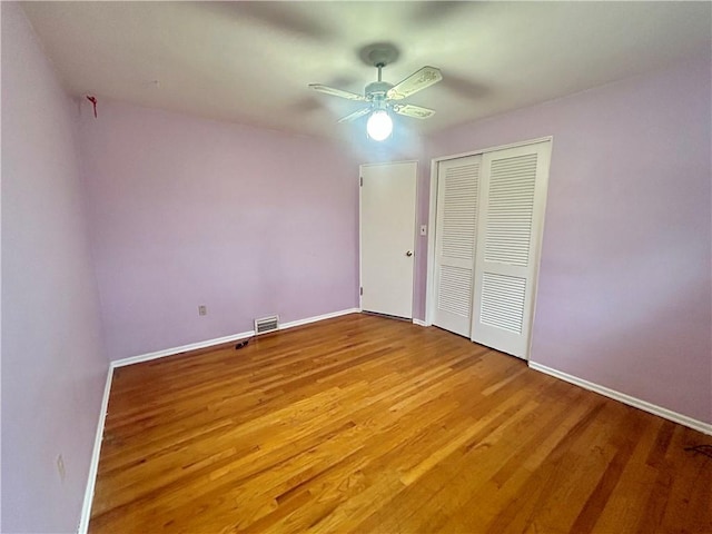 unfurnished bedroom with ceiling fan, a closet, and wood-type flooring