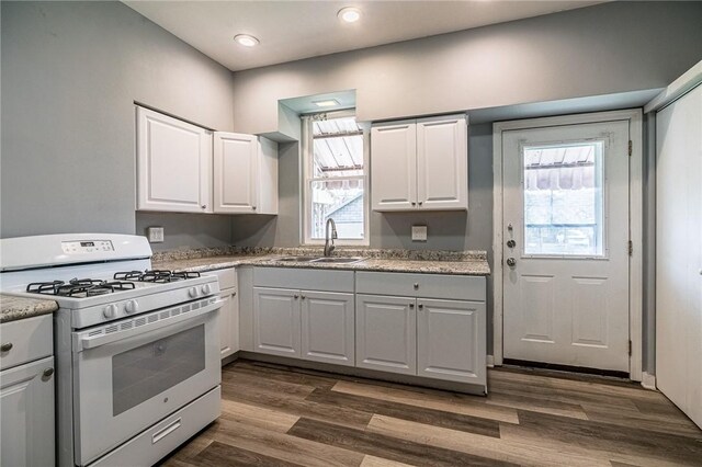 kitchen with white cabinetry, white gas range, and sink