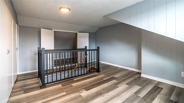 additional living space featuring hardwood / wood-style flooring, vaulted ceiling, and wooden walls