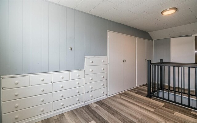 bedroom with hardwood / wood-style flooring, wooden walls, and vaulted ceiling