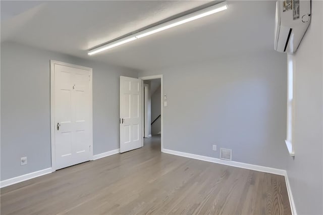 empty room featuring light hardwood / wood-style floors and a wall mounted air conditioner