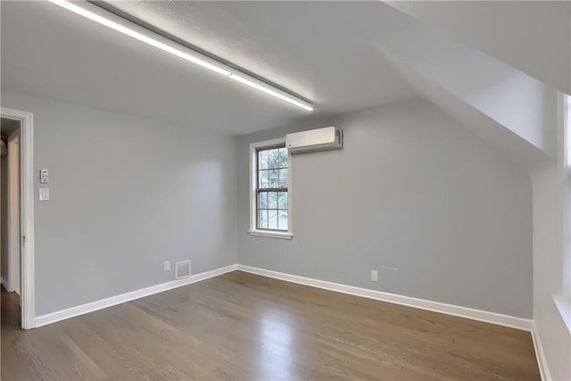 additional living space with a wall mounted air conditioner, lofted ceiling, and dark wood-type flooring