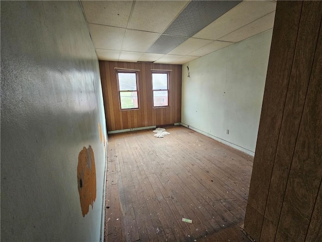 spare room featuring wood-type flooring and a drop ceiling