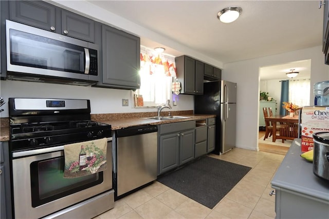 kitchen featuring gray cabinetry, sink, light tile patterned floors, and stainless steel appliances