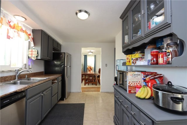 kitchen featuring stainless steel dishwasher, light tile patterned flooring, gray cabinets, and sink