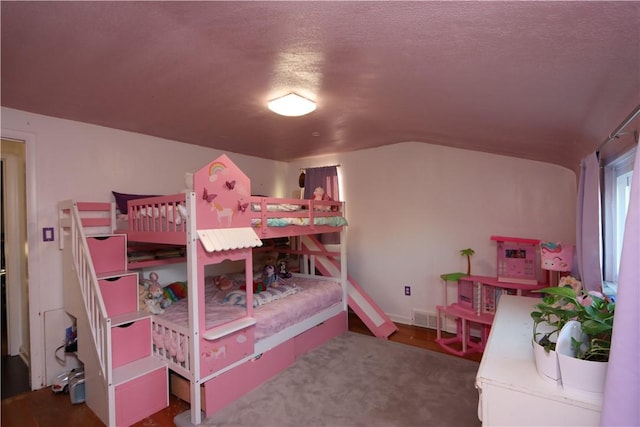 bedroom with lofted ceiling and a textured ceiling