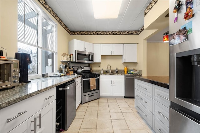 kitchen featuring white cabinetry, sink, stone countertops, light tile patterned floors, and appliances with stainless steel finishes