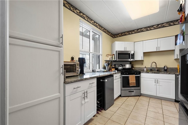 kitchen with dark stone countertops, sink, white cabinets, and stainless steel appliances