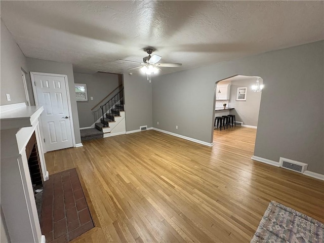 unfurnished living room with a textured ceiling, hardwood / wood-style flooring, and ceiling fan