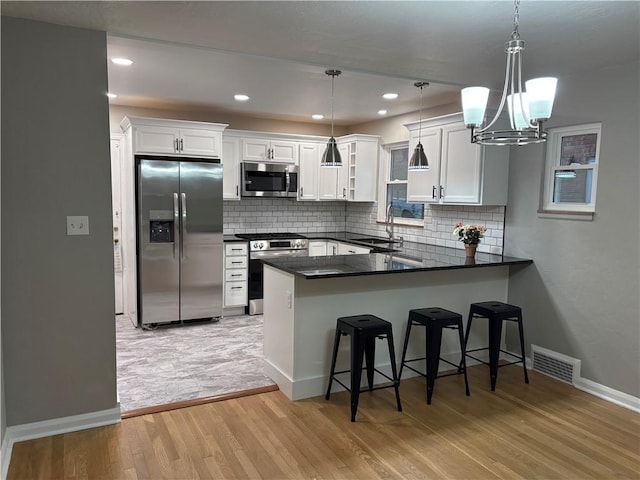 kitchen with white cabinetry, hanging light fixtures, and appliances with stainless steel finishes