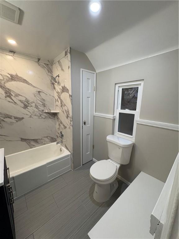 full bathroom with bathtub / shower combination, vanity, toilet, and lofted ceiling