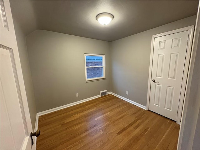 empty room featuring hardwood / wood-style flooring and lofted ceiling