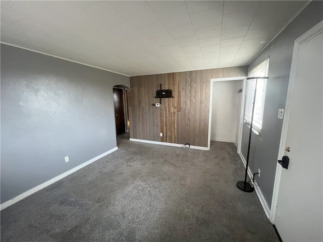 spare room featuring dark carpet and wooden walls