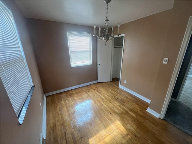 unfurnished dining area with light wood-type flooring and an inviting chandelier