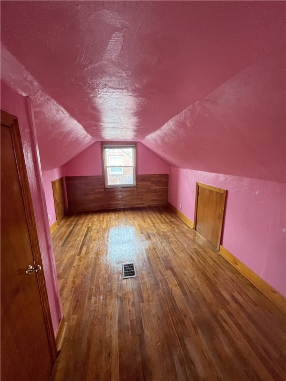 additional living space featuring light hardwood / wood-style floors and lofted ceiling