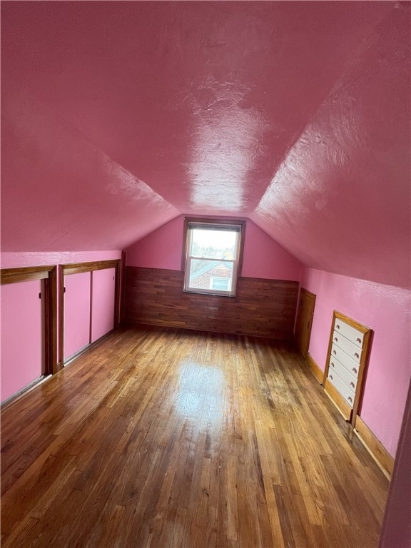 additional living space with light hardwood / wood-style flooring and vaulted ceiling