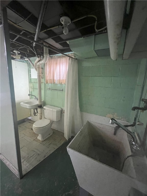 bathroom featuring toilet, sink, and concrete floors