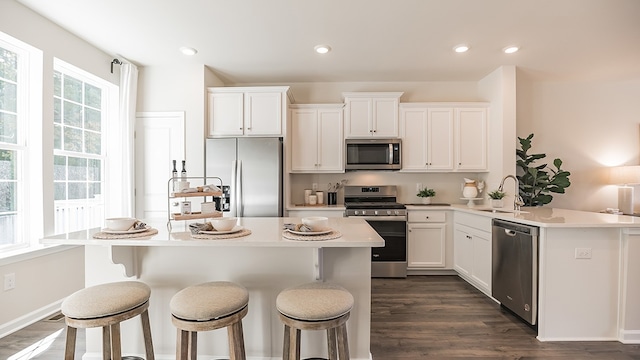 kitchen with dark wood-type flooring, white cabinets, sink, appliances with stainless steel finishes, and kitchen peninsula