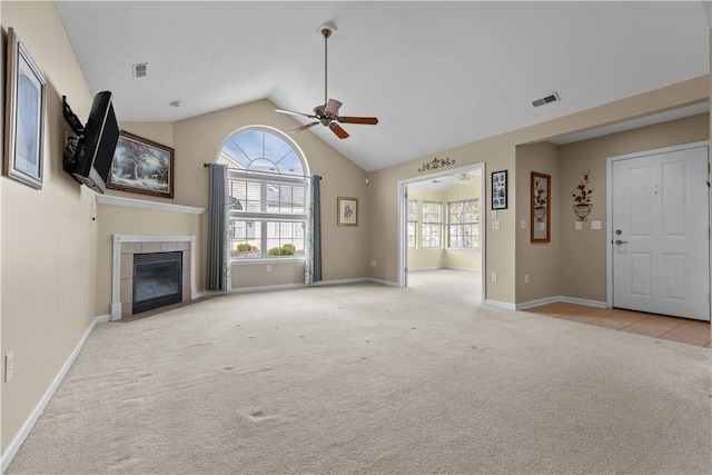 unfurnished living room with a tiled fireplace, ceiling fan, high vaulted ceiling, and light colored carpet