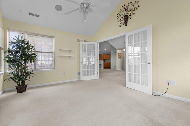 carpeted empty room with ceiling fan, high vaulted ceiling, and french doors