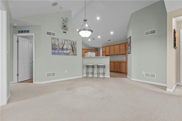 kitchen featuring high vaulted ceiling, white refrigerator, hanging light fixtures, light colored carpet, and a breakfast bar area