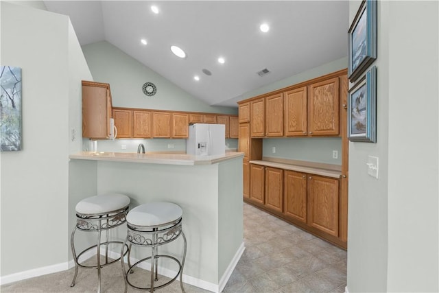 kitchen with a breakfast bar area, kitchen peninsula, lofted ceiling, and white appliances