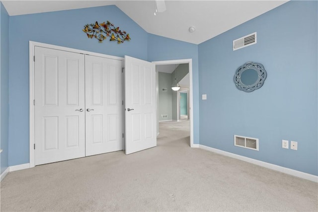 unfurnished bedroom with ceiling fan, light colored carpet, lofted ceiling, and a closet