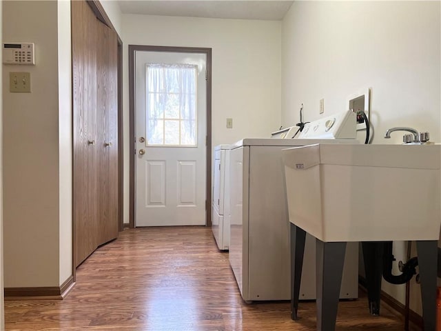 laundry room with washer and clothes dryer, sink, and hardwood / wood-style flooring