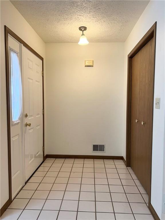 foyer entrance with light tile patterned floors and a textured ceiling