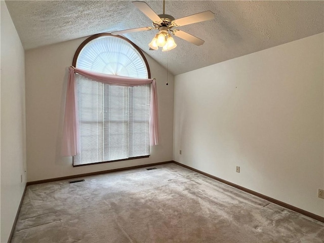 empty room with a textured ceiling, ceiling fan, light carpet, and vaulted ceiling